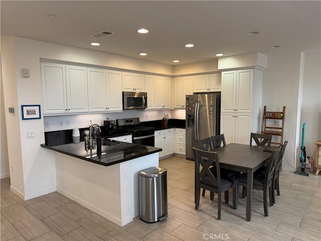 8823 Jacaranda Unit F, Montclair, CA 91763 - kitchen featuring appliances with stainless steel finishes, a peninsula, wood tiled floors, a sink, and dark countertops