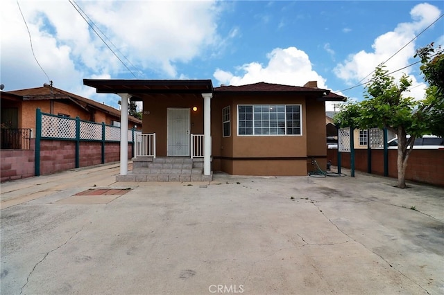bungalow-style home with fence and stucco siding