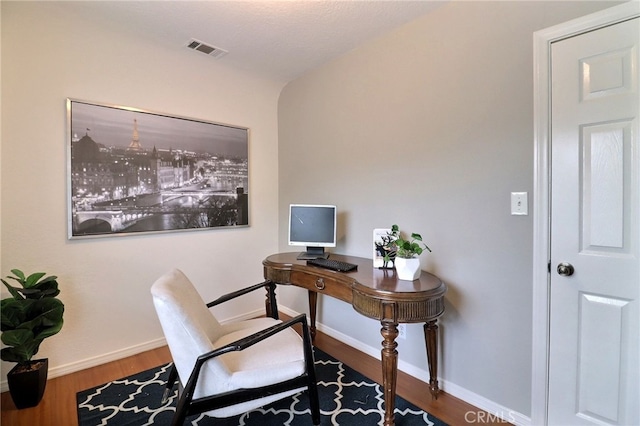 office area with wood finished floors, visible vents, and baseboards