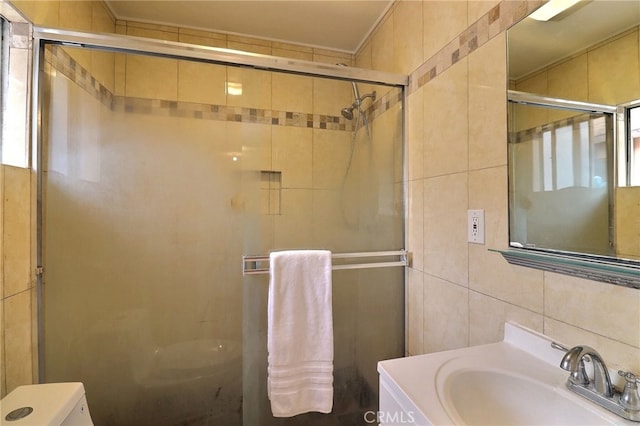 bathroom with a shower stall, tile walls, toilet, and vanity