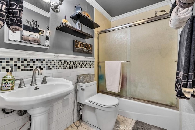 bathroom with shower / bath combination with glass door, a wainscoted wall, toilet, tile walls, and crown molding