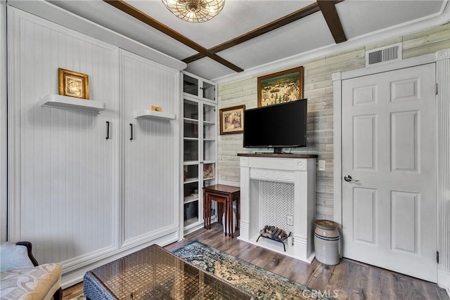 living area featuring beam ceiling, visible vents, coffered ceiling, wood finished floors, and wood walls