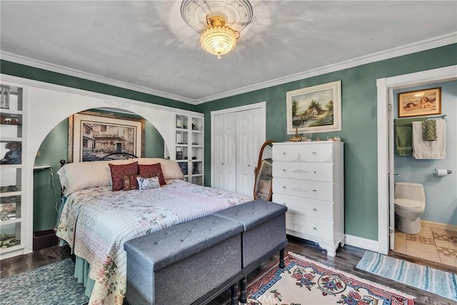 bedroom with baseboards, ornamental molding, wood finished floors, and a closet