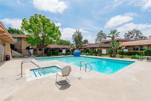 pool with fence, a hot tub, and a patio