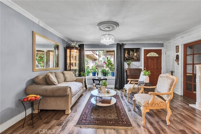 living area with a textured ceiling, baseboards, an inviting chandelier, wood finished floors, and crown molding