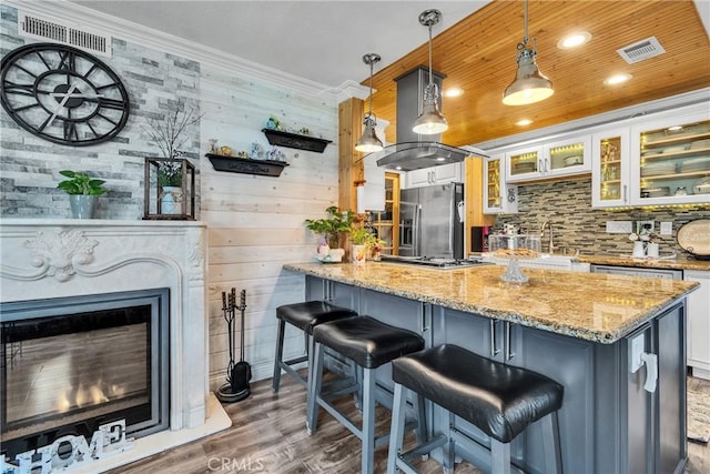 kitchen with a kitchen bar, dark wood finished floors, stainless steel appliances, and visible vents