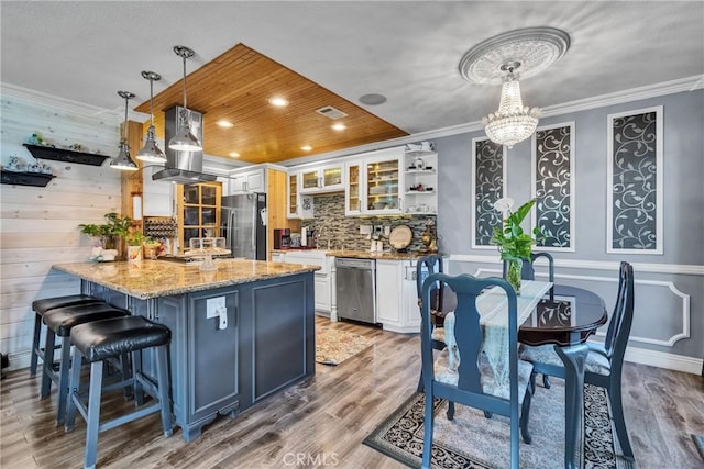 kitchen featuring light stone counters, backsplash, crown molding, appliances with stainless steel finishes, and white cabinetry