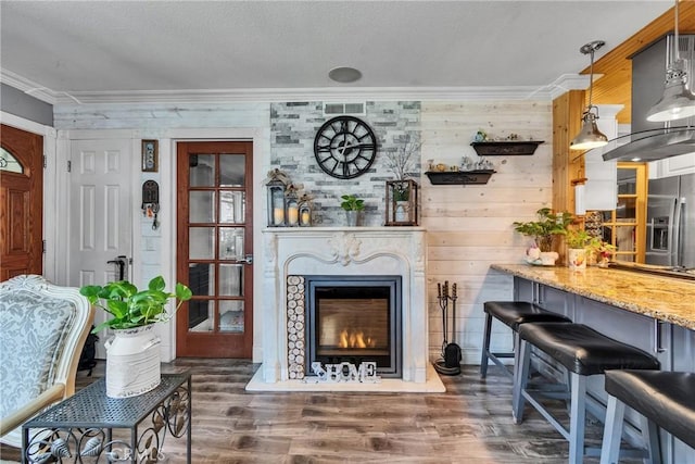 sitting room featuring wood finished floors, wood walls, a lit fireplace, and ornamental molding