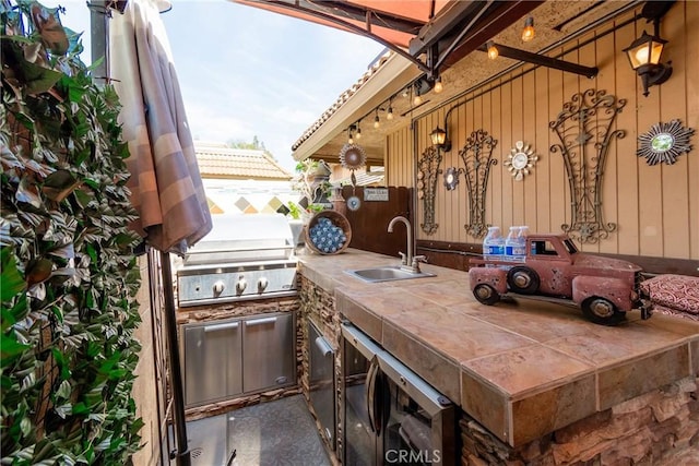 view of patio / terrace with exterior kitchen, a sink, a grill, and fence
