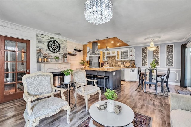 living room featuring a fireplace, light wood finished floors, ornamental molding, and an inviting chandelier