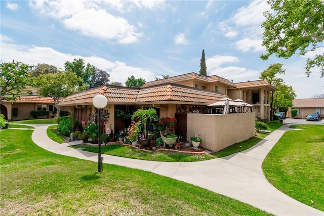 view of front of house featuring a tile roof, a front yard, and stucco siding