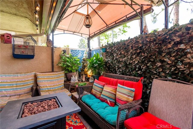 view of patio featuring fence, a gazebo, and an outdoor living space with a fire pit
