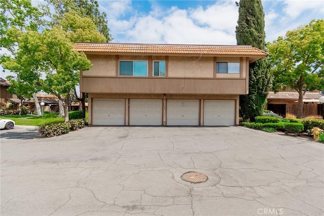 view of front of home featuring stucco siding, an attached garage, and a tiled roof