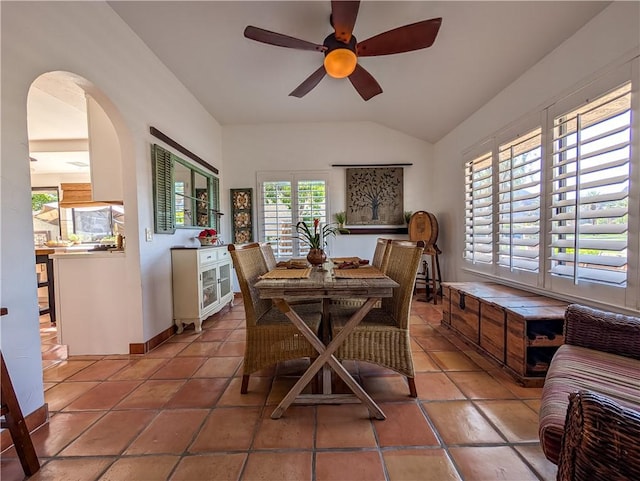 48143 Calle Seranas Ln, Quinta, CA 92253 - dining space with vaulted ceiling, a ceiling fan, arched walkways, light tile patterned flooring, and baseboards
