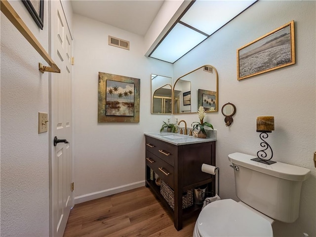 48143 Calle Seranas Ln, Quinta, CA 92253 - half bathroom featuring vanity, toilet, visible vents, baseboards, and wood finished floors