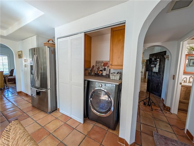 48143 Calle Seranas Ln, Quinta, CA 92253 - laundry room featuring arched walkways, baseboards, cabinet space, light tile patterned floors, and washer / dryer