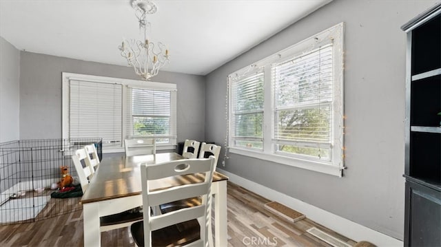 dining area featuring visible vents, wood finished floors, a notable chandelier, and a healthy amount of sunlight