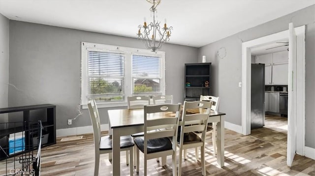 dining area featuring light wood-style flooring, baseboards, and a notable chandelier