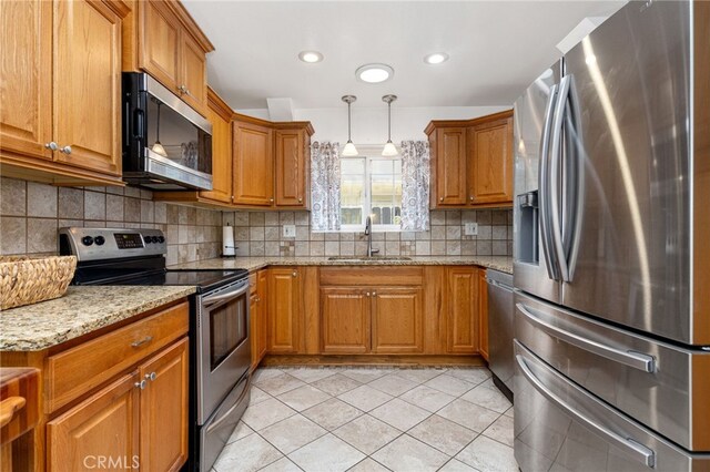 26481 Jamestown Dr, Menifee, CA 92586 - kitchen with stainless steel appliances, brown cabinetry, light stone countertops, tasteful backsplash, and light tile patterned floors