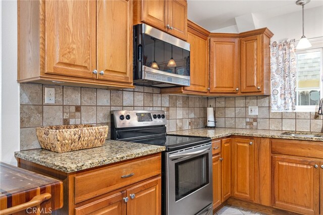 26481 Jamestown Dr, Menifee, CA 92586 - kitchen featuring appliances with stainless steel finishes, brown cabinets, light stone counters, backsplash, and hanging light fixtures