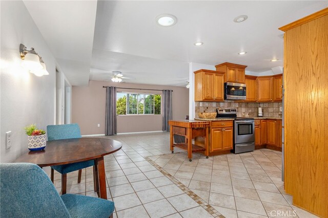 26481 Jamestown Dr, Menifee, CA 92586 - kitchen with appliances with stainless steel finishes, light tile patterned flooring, open floor plan, decorative backsplash, and a ceiling fan
