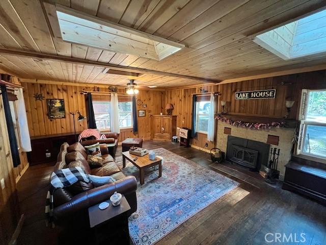 15 Toyon Trl, Berry Creek, CA 95916 - living area with wood ceiling, a skylight, wood walls, wood finished floors, and a fireplace with flush hearth