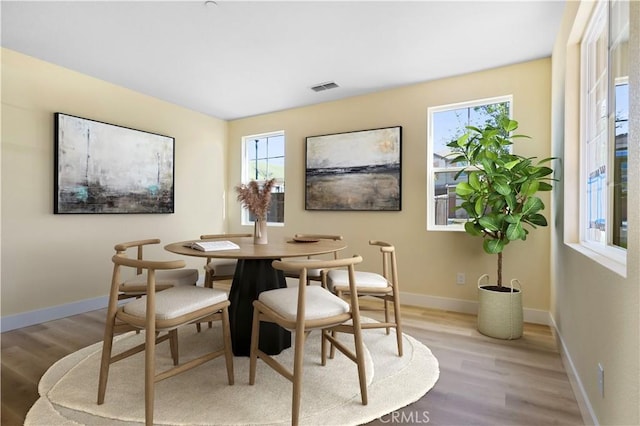 dining space with baseboards, light wood finished floors, and visible vents