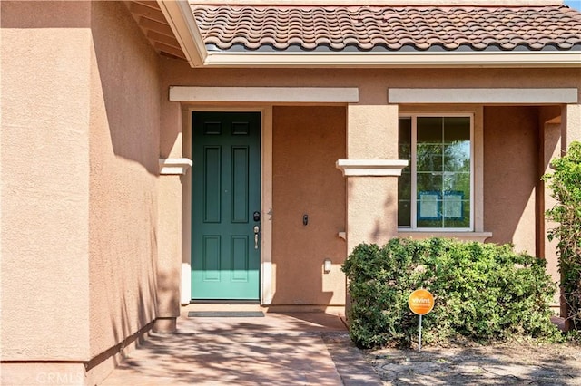 property entrance featuring a tiled roof and stucco siding