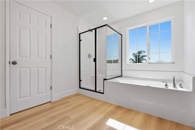 bathroom with a bath, wood finished floors, recessed lighting, and a stall shower