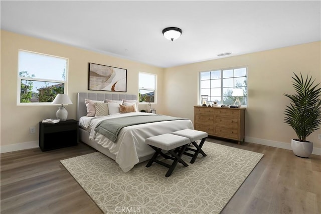 bedroom with wood finished floors, visible vents, and baseboards