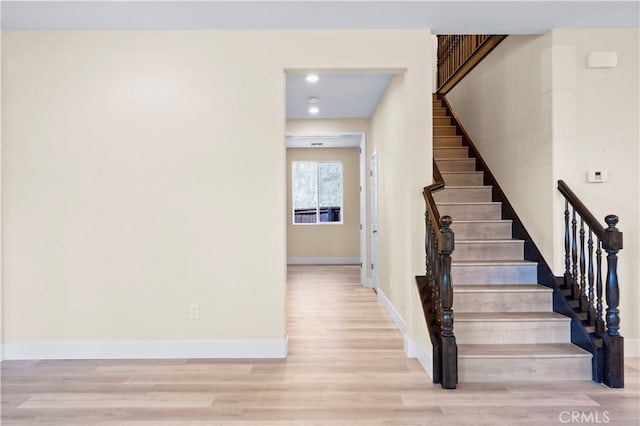 stairs with baseboards, wood finished floors, and recessed lighting