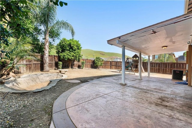 view of yard with a patio, a fenced backyard, a playground, and a mountain view
