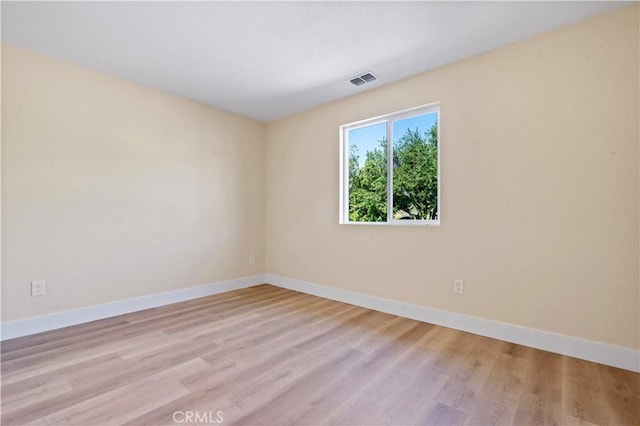 unfurnished room featuring baseboards, visible vents, and light wood-style flooring