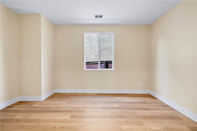 empty room with light wood-type flooring, baseboards, and visible vents