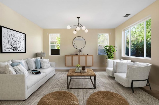 living room with baseboards, wood finished floors, visible vents, and a notable chandelier