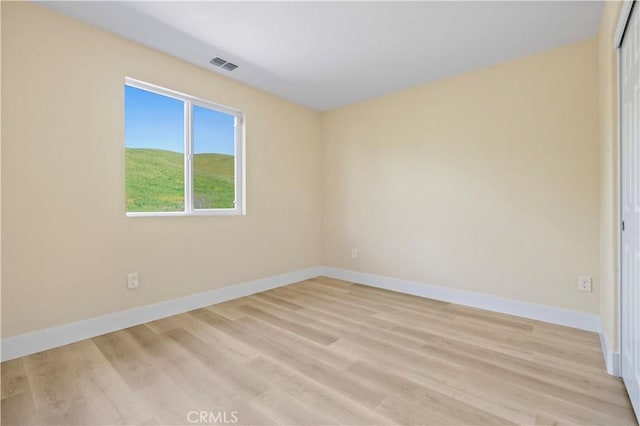 unfurnished room featuring baseboards, light wood-style floors, and visible vents