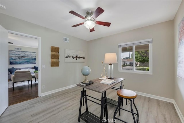 home office featuring light wood finished floors, baseboards, visible vents, and ceiling fan