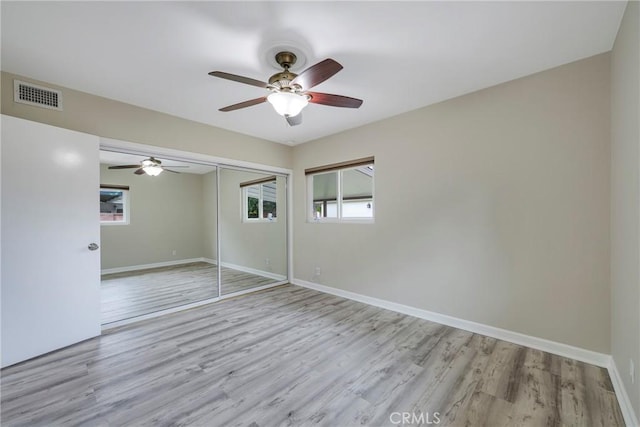 unfurnished bedroom featuring baseboards, wood finished floors, visible vents, and a closet
