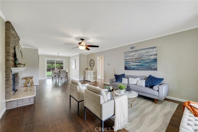 living room featuring baseboards, visible vents, ornamental molding, and dark wood-style flooring
