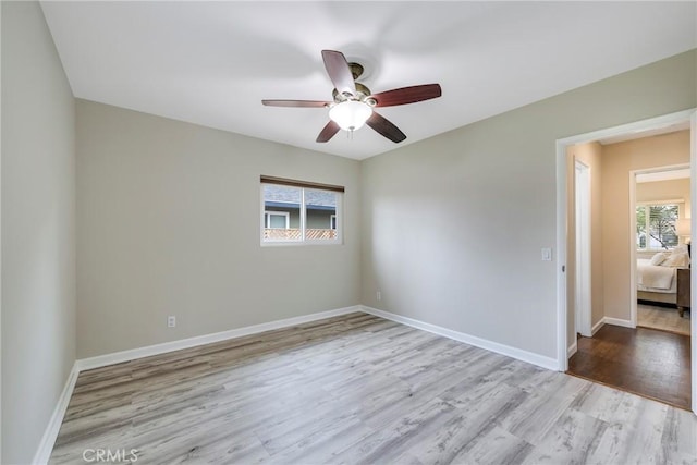 empty room with wood finished floors, a ceiling fan, and baseboards