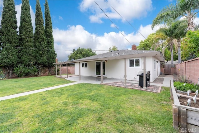 rear view of house with a chimney, a fenced backyard, stucco siding, a patio area, and a lawn