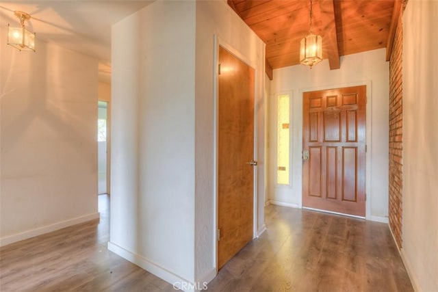 foyer entrance featuring baseboards, wood finished floors, a healthy amount of sunlight, and wood ceiling