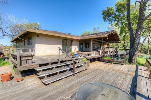 back of property with a wooden deck and stucco siding