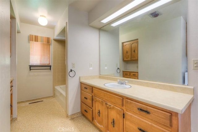 bathroom featuring visible vents, a tub to relax in, and vanity