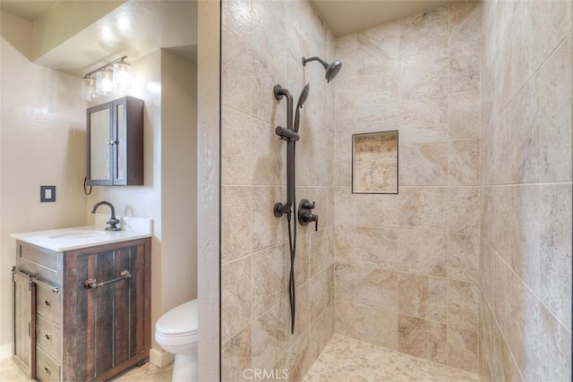 bathroom with vanity, a tile shower, and toilet