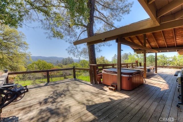 deck with a hot tub and a mountain view