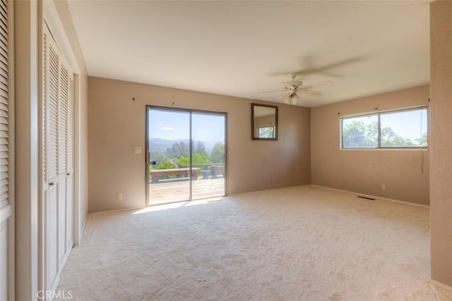 carpeted spare room with a ceiling fan and visible vents