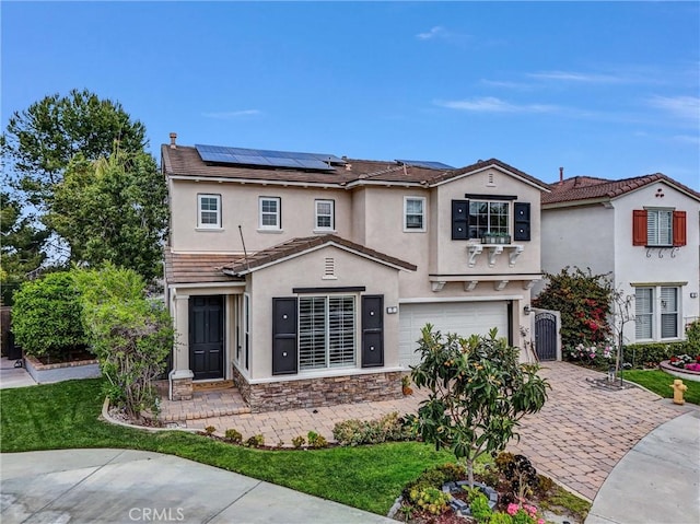 mediterranean / spanish house featuring a tile roof, stone siding, roof mounted solar panels, a garage, and stucco siding