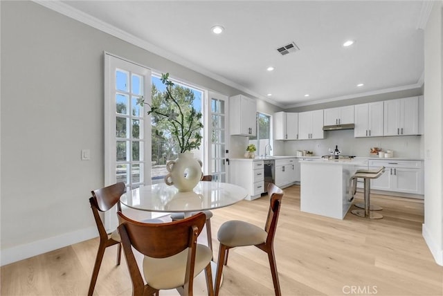dining space featuring light wood finished floors, baseboards, visible vents, and ornamental molding