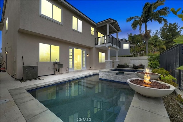 back of property featuring stucco siding, a patio, a balcony, and an outdoor fire pit